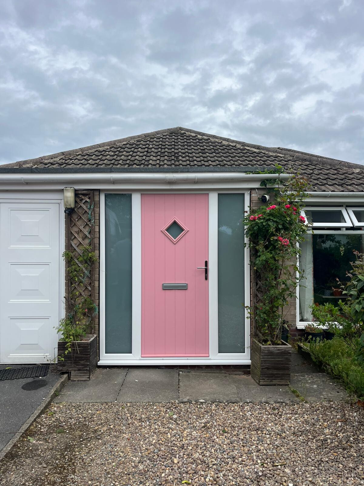 Flint 1 style composite door in Champagne Blush with white PVCu frame and sidelights with satin glass and graphite furniture.